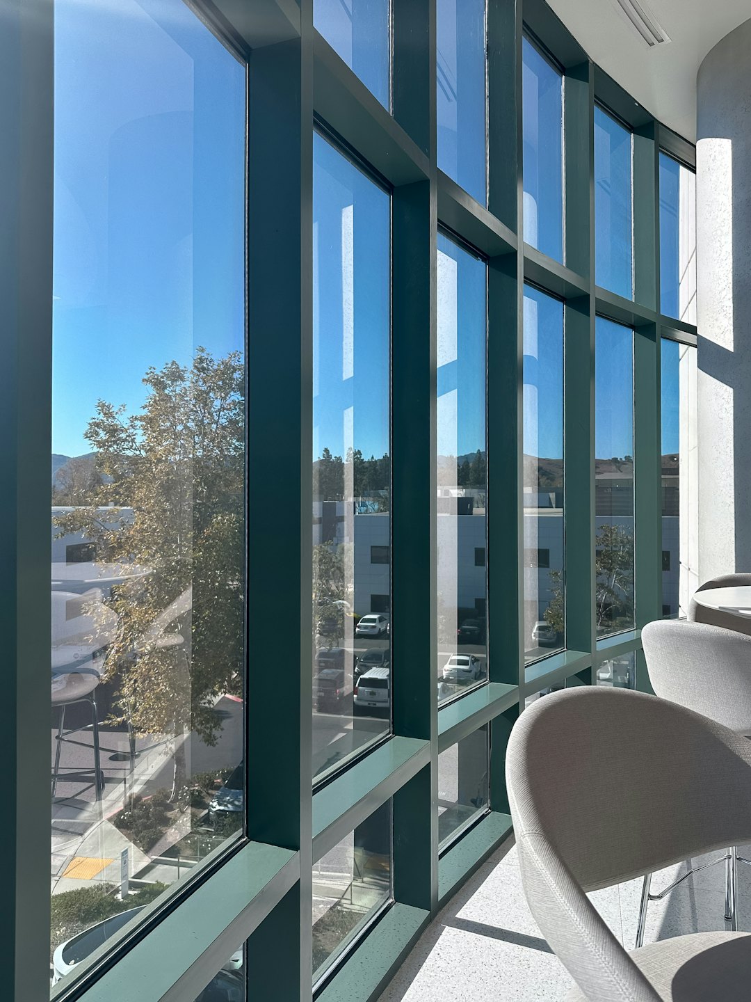 Sonnenlicht fällt durch große Fenster auf Stühle und Terrazzoboden.